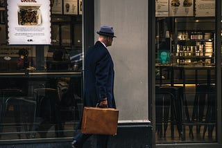 Intelligence agent walking with briefcase and hat undercover