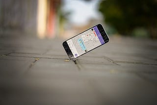 A dropped previous-generation iPhone cracking as it hits the pavement