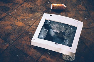 A broken computer monitor lies on the floor.