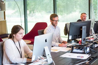 Three people (one female and 2 male) working on their computers in an office.