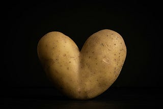 A potato shaped like a heart on a black background