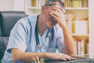 A tired doctor at his desk.