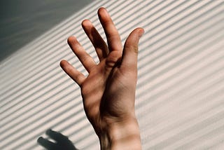 A hand reaching up for help in an office.