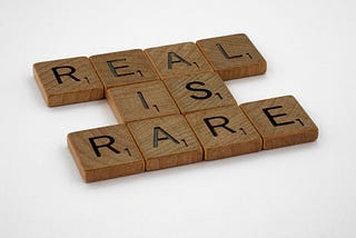 Scrabble pieces spelling out “Real is Rare”.