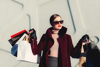 Stylish woman carrying several shopping bags in both hands.