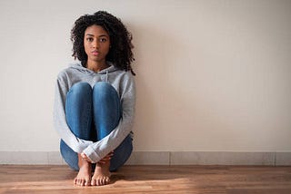 Woman sitting on the floor looking into space.