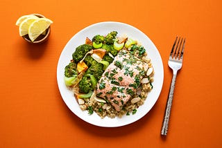 Plate with broccoli and fish on an orange background