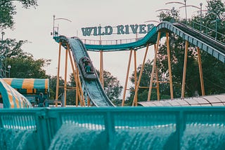 A water slide at an amusement park, light teal in color with the name Wild River over it