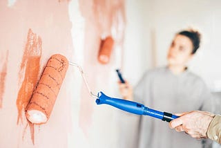 Couple renovating the house. Couple painting a wall