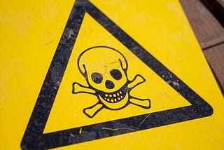Yellow danger sign. A black triangle has skull and bones inside of it.