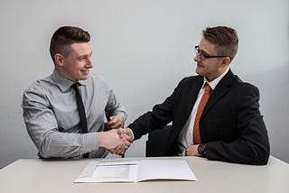 Two gentlemen shaking hands over what seems to be a successful deal