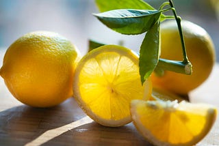 Close-up still life of lemon slices on a wooden table with light seeping through.