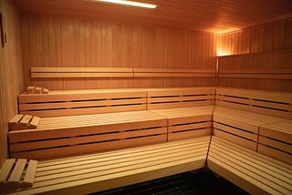 A sauna filled with rows of light wooden benches.