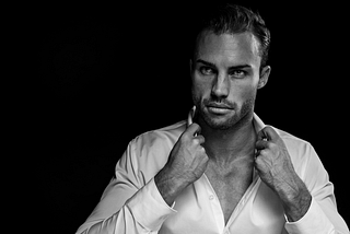 Black and white photo of a handsome man with a white shirt open at the top