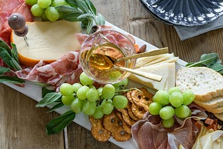 charcuterie board with cheese, meat, bread, grapes, and honey