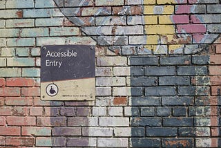 A colourfully painted brick wall has a sign saying ‘Accessible Entry’.