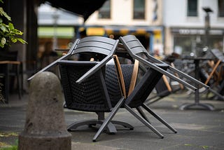 Leere, an einen Tisch angelehnte Stühle in einem Gastro-Außenbereich
