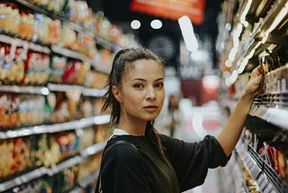 Photo of a lady picking food from a supermarket shelf. Patience invariably overtakes haste.