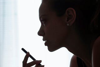 A silhouette of a woman’s face and hand speaking into her phone’s microphone