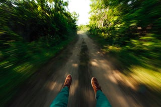 A man’s feet as he slips swiftly down a path in the woods