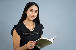 Woman wearing a black shirt and holding a book against a blue background