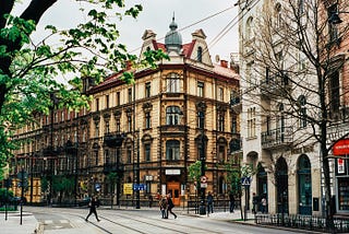 Kraków city scene with three story buildings, tram lines and a pedestrians.
