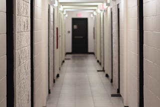 Long ominous hallway with identical doors on left and right sides.