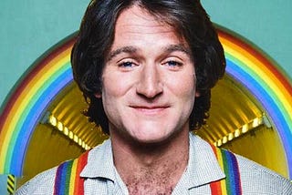 Robin Williams smiling with rainbow suspenders/braces.