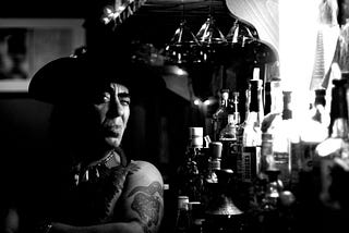 Black and white image of a Native American man sitting at a bar.