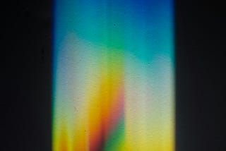 Colors of a rainbow shown vertically as through a prism.