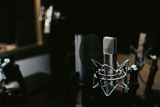 recording studio with low lighting, featuring a standalone recording microphone in the foreground.