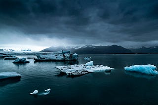 Ice floating in the water- mountains in the background on a cloudy day