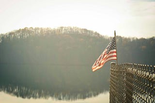 american flag on fence with hazy forest in background
