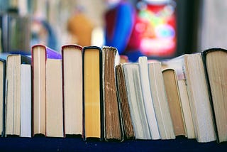 A side view of old books stacked on a shelf