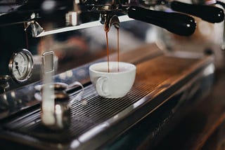 An espresso machine at a coffee shop. It is in the process of pulling a shot of espresso.