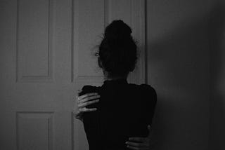 woman standing in front of a door giving herself a hug