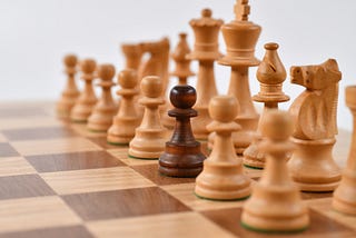 Chess pieces with one darker coloured pawn