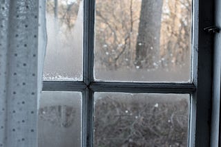 paned window with side curtain looking out into rain
