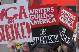 An image of writers holding signs during a strike initiated by the Writers Guild of America