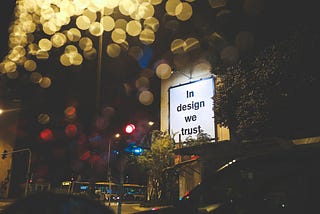 A close up of a billboard saying “in design we trust”