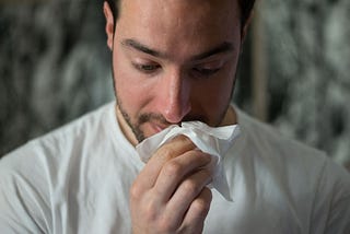 Man holding a hanckerchief against his nose