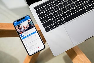 A phone with facebook open next to a laptop