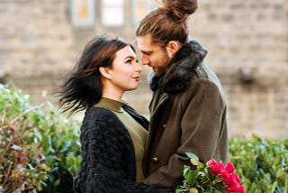 A couple hugging, with the girl holding a bouquet of roses