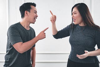 A man and woman arguing, pointing their fingers, yelling