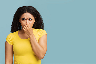 A woman holding her nose to avoid the unpleasant smell.