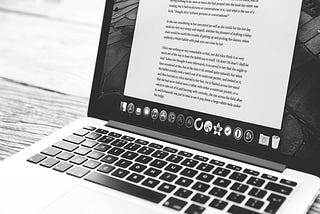 Black and white image of an opened laptop with a long text visible on the screen