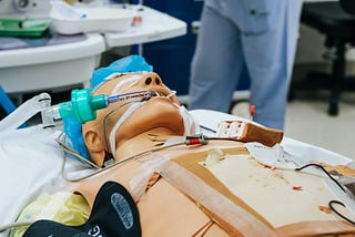 Man lying in bed hooked up to many wires and tubes