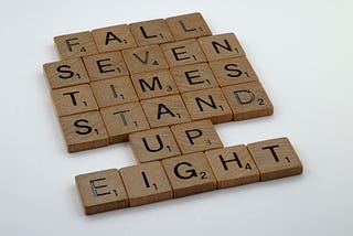 Scrabble tiles that spell out Fall Seven Times Stand Up Eight