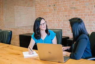 two ladies sitting at a table having an interview