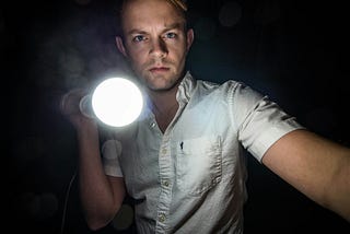 photo of a sinister looking young man shines a flashlight at the viewer — alt-text to boost accessibility